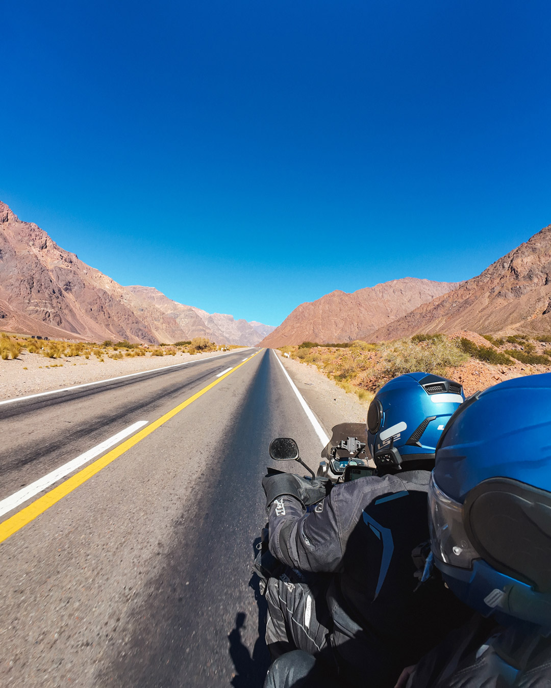 Casal de moto diante das montanhas da Cordilheira